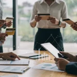Pessoas analisando informações financeiras e cartões de crédito, com gráficos digitais ao fundo, simbolizando a análise de score de crédito.