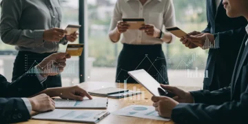 Pessoas analisando informações financeiras e cartões de crédito, com gráficos digitais ao fundo, simbolizando a análise de score de crédito.